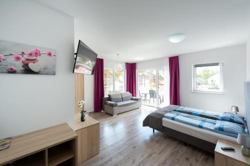 ein Schlafzimmer mit einem Bett, einem TV und einem Sofa in der Unterkunft Apartamenty HELJAN in Międzywodzie