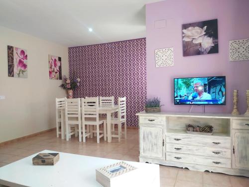 ein Wohnzimmer mit einem TV und einem Tisch mit Stühlen in der Unterkunft Magnífico adosado de esquina con vistas al golf playas Islantilla in Islantilla