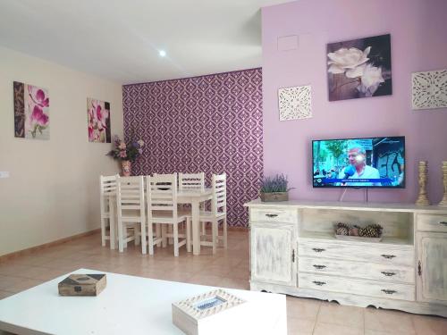 a living room with a tv and a table with chairs at Magnífico adosado de esquina con vistas al golf playas Islantilla in Islantilla