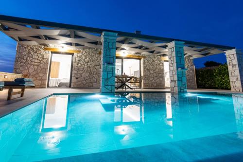 a villa with a swimming pool at night at Castielia Residence in Agalás