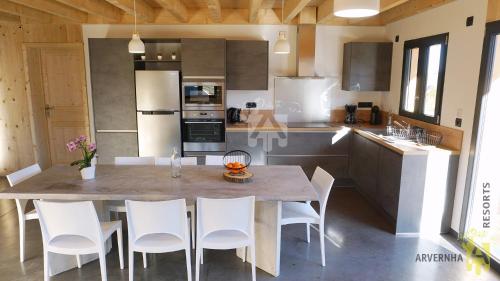 une cuisine avec une table et des chaises blanches dans l'établissement Chalet Nid Nous, à Chambon-sur-Lac