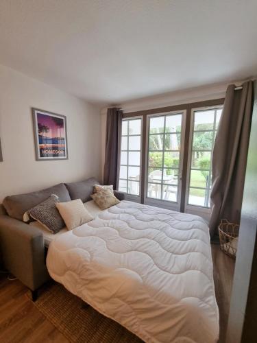 une chambre avec un grand lit et un canapé dans l'établissement Appartement du Golf Les Bastides piscine et océan, à Moliets-et-Maa