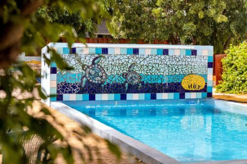 a swimming pool with a mosaic wall next to it at The Hut Bonaire in Kralendijk