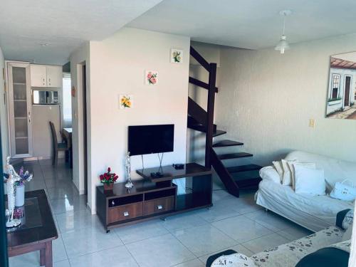 a living room with a couch and a television at condominio moradas de guarajuba in Guarajuba