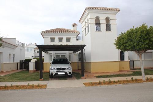 un coche aparcado frente a una casa blanca en Villa en La Torre Golf Resort by Rental Olé, en Torre-Pacheco