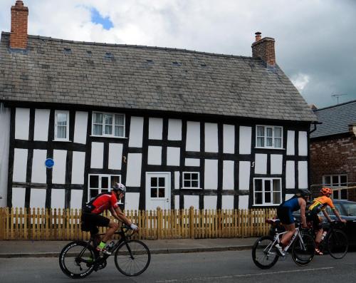 two people riding bikes in front of a black and white building at The Lion at Malpas in Malpas