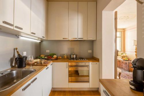 a kitchen with white cabinets and a sink at Palazzo Benassi Penthouse in Asolo