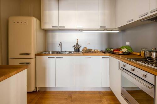 a kitchen with white cabinets and a sink and a refrigerator at Palazzo Benassi Penthouse in Asolo