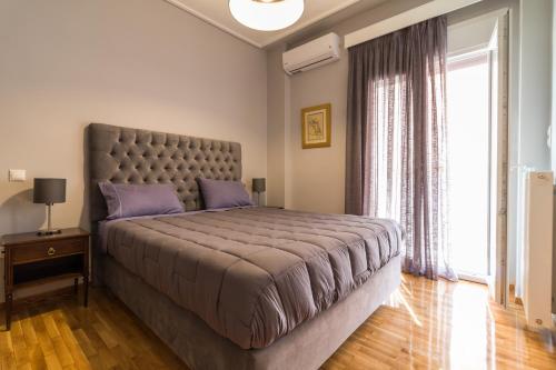 um quarto com uma cama grande e uma janela grande em Comfortable and Spacious 2 bdr Apt em Atenas