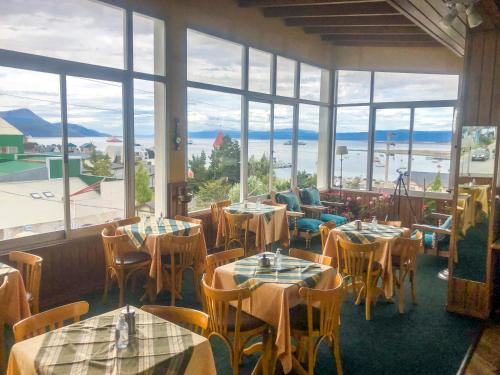 a restaurant with tables and chairs and large windows at Hotel Mustapic in Ushuaia