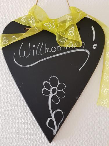 a sign with a flower on it with a yellow bow at Sonnendeck in Greetsiel