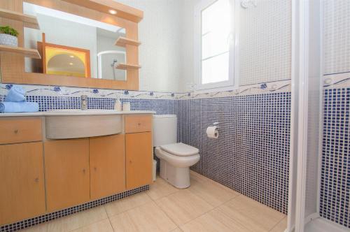 een badkamer met een toilet, een wastafel en een spiegel bij Villa Miel by Sonne Villas in Cala Galdana