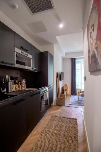 - une cuisine avec des armoires noires et un tapis au sol dans l'établissement Superbe studio Plage/ Promenade des Anglais 104, à Nice