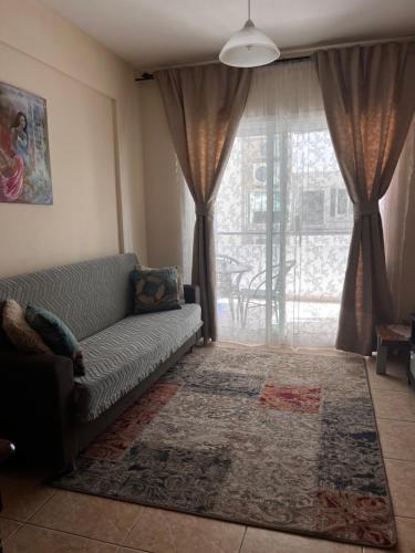 a living room with a couch and a large window at Makenzy Apartment in Larnaka