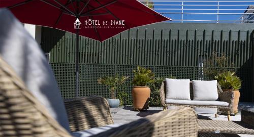 a patio with chairs and a red umbrella at Hotel De Diane in Sables-dʼOr-les-Pins