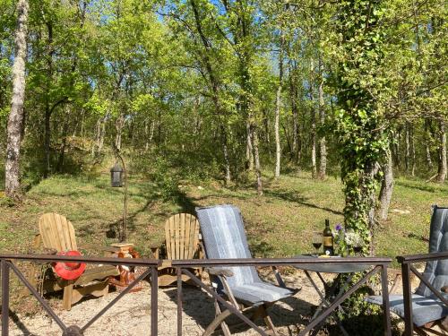 un groupe de chaises et d'une table dans les bois dans l'établissement le bout du Bout, à Les Arques