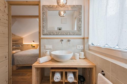 a bathroom with a sink and a mirror and a bed at Central Home Apartment in Ortisei