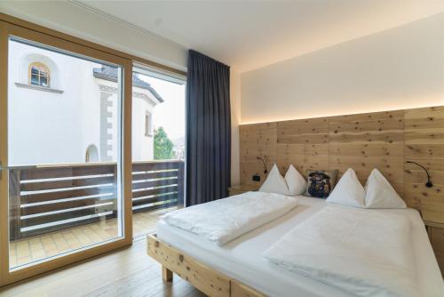 1 dormitorio con cama y ventana grande en Apartments Jalve, en Ortisei