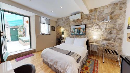 a bedroom with a large bed and a stone wall at Diocletian Studio Apartments in Split