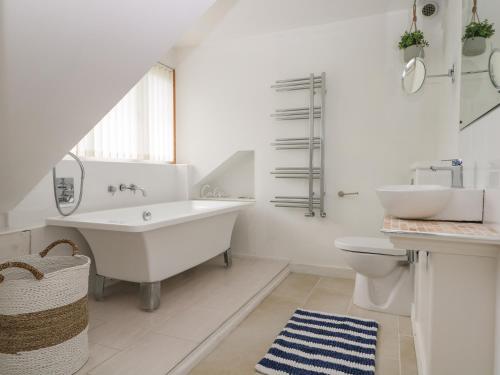 a white bathroom with a tub and a sink at Wheatlands in South Hayling