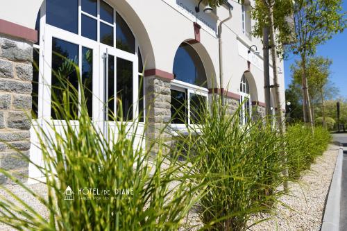 a building with tall green plants in front of it at Hotel De Diane in Sables-dʼOr-les-Pins