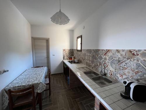 cocina con fregadero y encimera con mesa en La Dimora di Eloisa, en Castel di Iudica