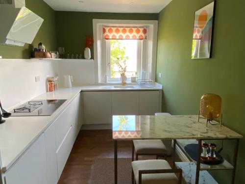 a kitchen with green walls and a table and a window at Arbroath luxury apartment in MCM style in Arbroath