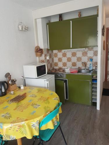 una pequeña cocina con mesa y microondas en Studio 4 couchages vue pistes, en Gréolières les Neiges