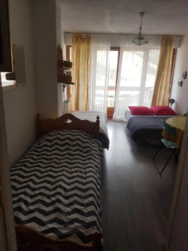 1 dormitorio con 2 camas y ventana en Studio 4 couchages vue pistes, en Gréolières les Neiges