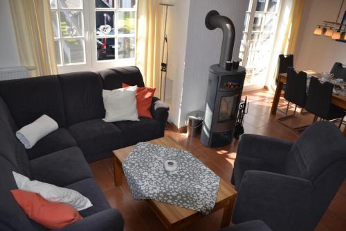 a living room with a black couch and a stove at Kapitänskoje in Greetsiel
