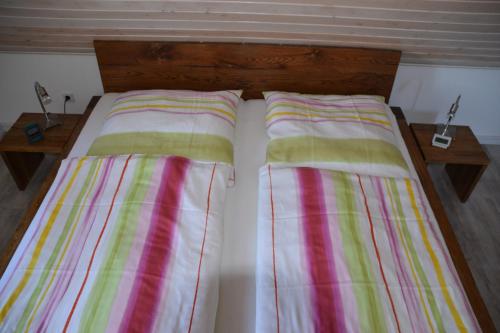 a bed with striped sheets on it with two tables at Kapitänskoje in Greetsiel