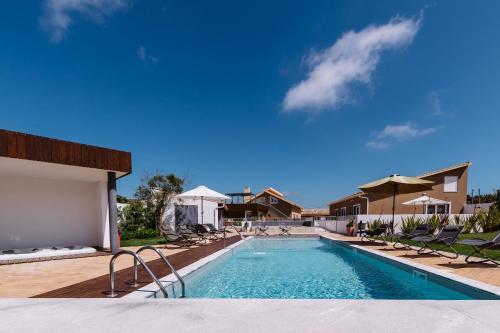 a swimming pool with chairs and a blue sky at Barrocas Village in Olho Marinho