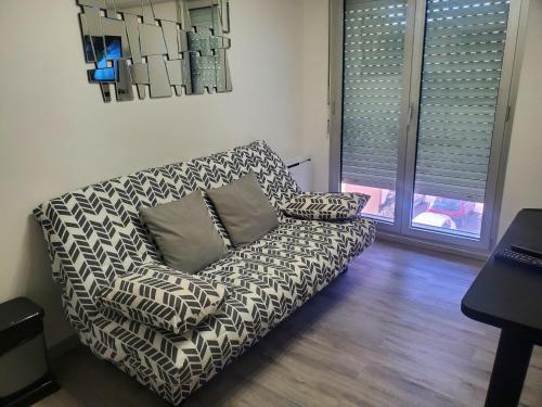 un sofá sentado en una sala de estar junto a una ventana en JOLI PETIT STUDIO AU CENTRE DE CARRY LE ROUET, en Carry-le-Rouet