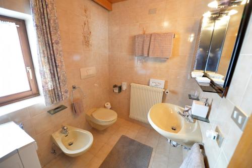 ein Badezimmer mit einem Waschbecken, einem WC und einem Waschbecken in der Unterkunft Apartment Nogler Frieda in Wolkenstein in Gröden