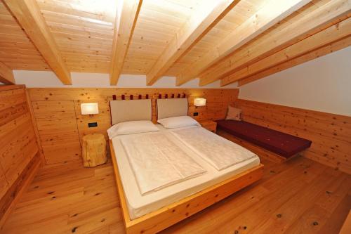 ein Schlafzimmer mit einem großen Bett in einem Holzzimmer in der Unterkunft Mountain Apartment Hapeli in St. Ulrich in Gröden