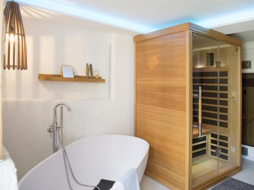 La salle de bains est pourvue d'une armoire en bois et d'une baignoire. dans l'établissement Rain Apartment with private spa area-Zorten-Lenzerheide, à Obervaz