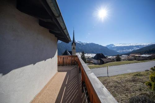 a balcony of a house with a view of a church at Ferienhaus Alvaneu für Familien in Alvaneu
