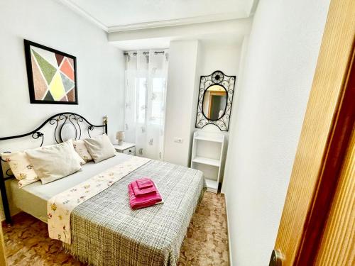 een slaapkamer met een roze tas op een bed bij DE VACACIONES in Torrevieja