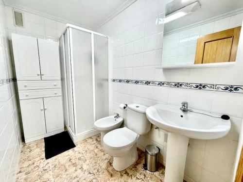 een witte badkamer met een toilet en een wastafel bij DE VACACIONES in Torrevieja