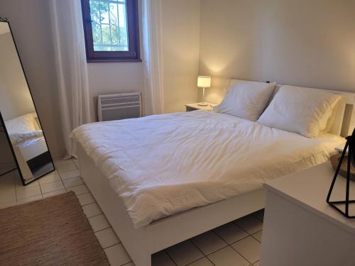 une chambre avec un lit avec des draps blancs et une fenêtre dans l'établissement La Commanderie, à Cotignac