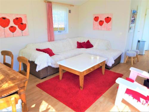 a living room with a white couch and a table at Chalet 556 op Recreatiepark De Wielen in Sint Maarten