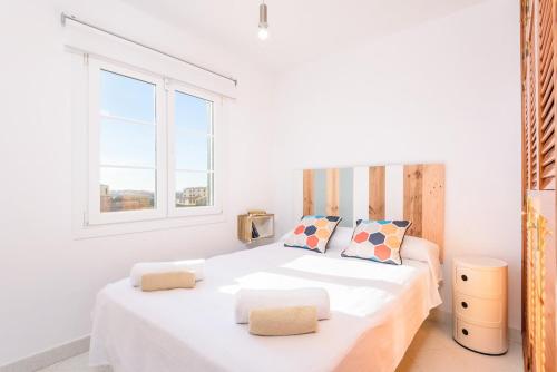 a white bedroom with two beds and a window at Brisa Marina in Cala en Blanes