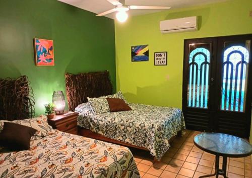 1 dormitorio con 2 camas, mesa y paredes verdes en casita de lola, en Ciudad Valles