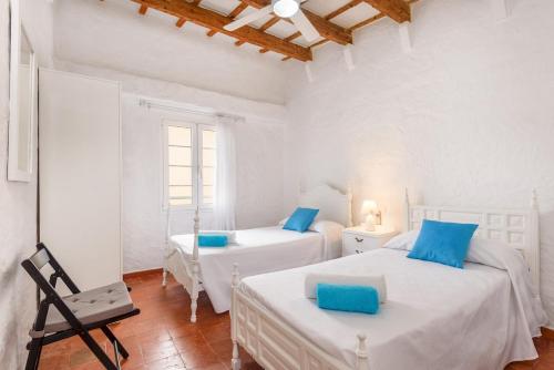 2 camas en una habitación con paredes blancas y almohadas azules en CA S'AVI BIEL, en Ciutadella