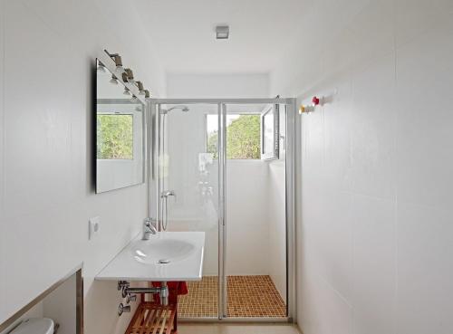 a white bathroom with a sink and a shower at Villa Aire in Punta Prima