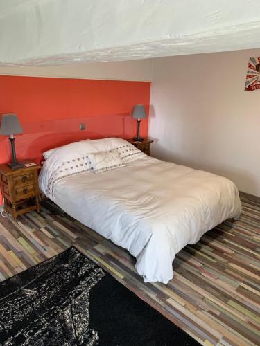 a bedroom with a large bed with an orange wall at Swift Gites Creuse 