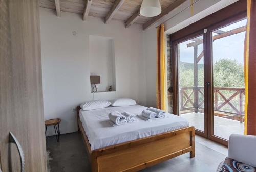 a bedroom with a bed and a large window at Elea Stone Houses in organic quiet olive grove, Prinos, Thassos in Prinos