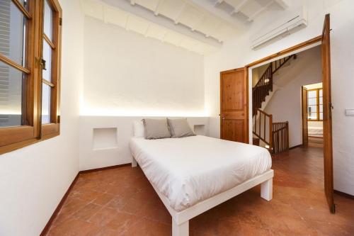 a bedroom with a white bed and a staircase at SANT ISIDRE 50 in Ciutadella