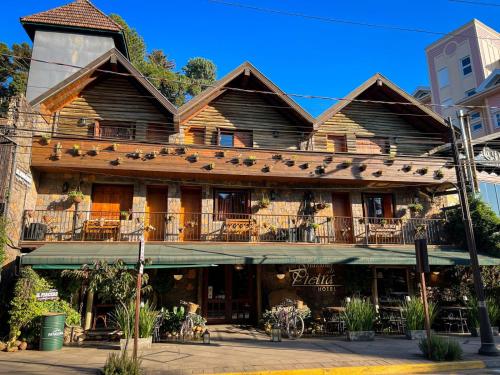 um grande edifício de madeira com uma varanda numa rua em Hotel Giardino Di Pietra em Gramado