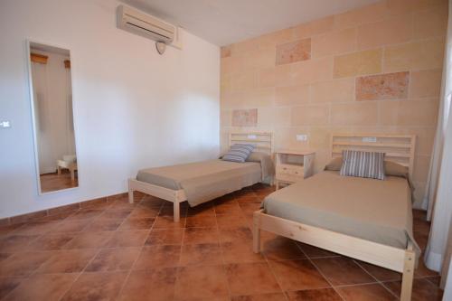 Habitación con 2 camas y espejo. en Villa S'Hortal en Ciutadella